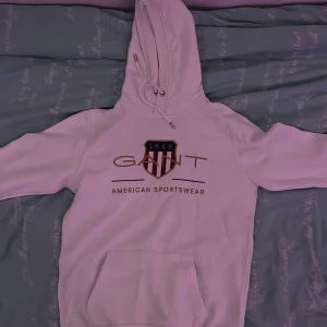 Vit hoodie från GANT med tryck - Säljer en vit hoodie från GANT med stort tryck framtill och klassisk logga. Perfekt för dig som gillar sportig och clean stil. Mjuk och skön. Pris går att diskutera vid en bra affär! (Använd max 4 gånger) 