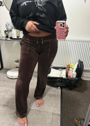 Bruna mjukisbyxor Juicy Couture S - Säljer ett par bruna mjukisbyxor från Juicy Couture i storlek. Materialet är mjukt och glansigt, perfekt för en chill och stylish look.