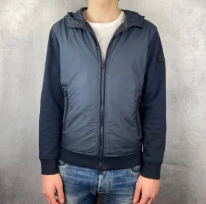 Mörkblå vindjacka från Woolrich - Snygg mörkblå vindjacka från Woolrich med luva och 2 fickor framtill. Jackan är perfekt för vår/höst men funkar även på sommaren. Jackan är i strl S. Pris kan diskuteras vid snabb affär😊