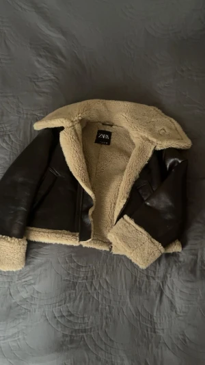 Brun teddyjacka från Zara med fuskpäls - Superfin shearling-jacka från ZARA!🤍🤎 Säljer min favoritjacka som jag bara hunnit använda ett par gånger. Den är i riktigt fint skick – nästan som ny. Köptes för 1000 kr.  Dubbelviktsjacka med mjuk teddy-insida och snygg “läderlook” på utsidan🤎🐻🤍 Perfekt för höst och vinter, håller värmen jättebra och passar både till jeans, klänningar och allt där emellan.  