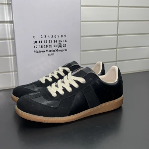 Maison Margiela GATs - Säljer nu ett par helt nya Maison Margiela GATs i färgen svart med en brun sula. Skorna är helt nya och har inga defekter alls. Säljs med tillhörande låda och dustbag. Tveka inte att höra av er // Herman.