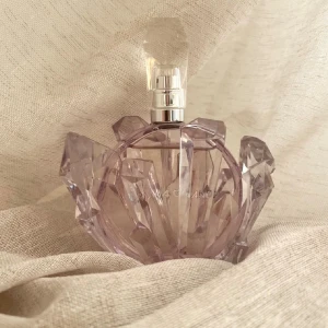 Ariana Grande R.E.M.  - En helt underbar doft av Ariana Grande, 100ml (se använd mängd på bild) Toppnoter: Kvitten, fikon, salt karamell och marshmallow. Hjärtnoter: Lavendel och päronblom. Basnoter: Tonkaböna, mysk och sandelträ. Säljes utan box. Förvarats mörkt och svalt. 