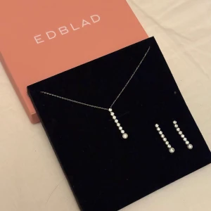 Edblad smyckeset med halsband & örhängen - ✨Snyggt smyckeset från Edblad med halsband och matchande örhängen i silverfärg. Både halsbandet och örhängena har en rad gnistrande stenar i en rak linje och en större rund sten längst ner. Perfekt för dig som gillar stilren och glittrig design✨