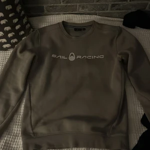 Beige Sail Racing sweatshirt S - Snygg beige sweatshirt från Sail Racing med logga framtill. Tröjan har rund halsringning, långa ärmar och är tillverkad i en mjuk bomulls- och polyestermix. Perfekt för dig som gillar stilren och sportig look.