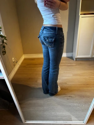 Lågmidjade jeans bootcut  - Snygga unika lågmidjade utsvängda jeans i snygg tvätt. Fickorna har snygga detaljer och knäppning.  Midjemått: 38 cm  Innerbensmått: 79 cm