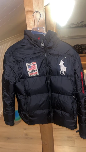 Ralph lauren puffer jacket downhill collection  - Säljer min svarta Ralph lauren jacka då jag har en ny och inte använder lika mycket jacka är i nästan helt ny skicka förutom en av dragkedjorna i fickan är sönder annars är den som ny den är storlek S men passar oxå till storlek m skicka förslag för pris