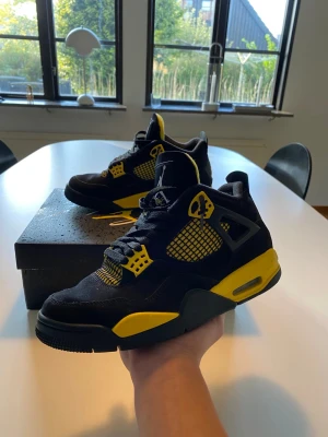 Nike Air Jordan 4 svart/gul sneakers - Nike Air Jordan 4 sneakers i svart och gul med klassisk Jordan-logga på plösen och hälen. Skorna har meshpaneler, snörning och detaljer i gult på sidorna och sulan. Ovandelen är i mocka och syntet, med en platt sula och rund tå. Box medföljer ✅. Skick 9/10 Ett litet märke på vänster sida av skon men det är knappt märkbart. Perfekt för alla väder.🙌 Nypris cirka 3600 ✅Skickar inom 48 timmar om inte samma dag 🚚 