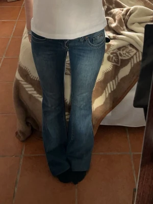 Blå bootcut jeans med flätad detalj - Säljer ett par av mina absoluta favoritjeans för jag inte får på mig dom längre! (Annan person som har på sig dom på bild 3 och 4) Dom är lågmidjade, blåa, bortbyt med flätad detalj där man träder bältet genom. Bakfickor med detalj på!☺️de är lite sluta vid hälen annars mycket bra skick! Innerbenslängd: 77cm, midjemått: 37cm