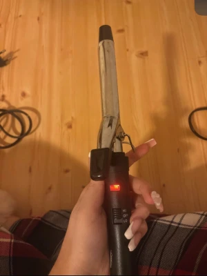 L'Oréal svart locktång - Säljer en svart locktång från L'Oréal med metallstav och svart plasthandtag. Tången har ett reglage för HI/LO värme och en röd indikatorlampa. Perfekt för att fixa snygga lockar snabbt och enkelt. Sladden är lång och flexibel för smidig styling. Perfekt till resa då den är lite mindre