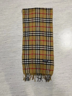 Beige Burberry Halsduk - Säljer en beige burberry halsduk. Halsduken är i mycket bra skick. Halsduken har den klassiska burberry mönstret i färgen beige. Halsduken är för bådde killar och tjejer. Halsduken är också äkta✅Skriv vid funderingar eller om ni vill ha fler bilder.