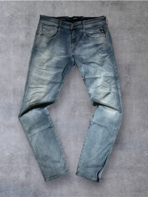 Blåa Replay Anbass Hyperflex Jeans - Klassiska Replay Anbass jeans i blå tvätt. Jeansen är i bra skick lite najs hål & revor men har tyvärr en rosa/röd fläck vid ena byxbenet. Anbass är slim fit! |  Storlek: W34/L36 (normal i storleken) | Skick: Bra skick! Några små hål/revor som ger en najs design. Tyvärr har byxorna en liten ”rosa/röd” fläck på ena byxbenet. Borde gå bort med fläckborttagning dock. (SE NÄSTSISTA BILD) | Färg: Blå | Märke: Replay | Modell: Anbass |  Hör gärna av dig vid frågor så svarar jag så fort jag kan! 😁|