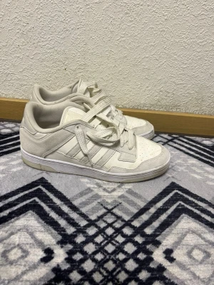 Vita Adidas sneakers i mocka och skinn - Säljer ett par stilrena vita Adidas sneakers 