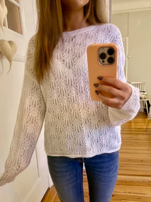 Vit stickad tröja - Säljer en vit stickad tröja med snyggt hålmönster och rund hals i fint skick. Tröjan har långärmad passform och är lite loose i modellen, perfekt att styla med jeans eller kjol💞💞
