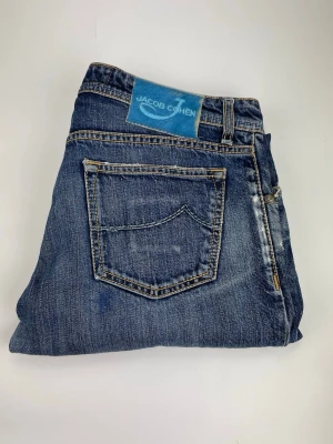 Jacob Cohen 622 - Snygga blå jeans från Jacob Cohen med klassisk femficksdesign och tydliga slitningar för en cool, avslappnad look. Jeansen har knäppning med knappar och kontrastsömmar. Tillverkade i mjukt denimtyg som sitter skönt hela dagen.