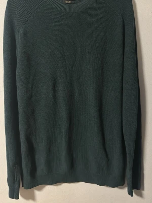 Mörkgrön stickad tröja Massimo Dutti  - En enkel och stilren mörkgrön stickad tröja från Massimo Dutti. Tröjan har rund halsringning och långa ärmar. Materialet är mjukt och ger en skön känsla. Aldrig använd.