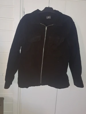 Svart jacka från H&M -  svart jacka från H&M med hel dragkedja framtill. Jackan har en enkel, rak passform och mjukt material som ger en avslappnad look. 