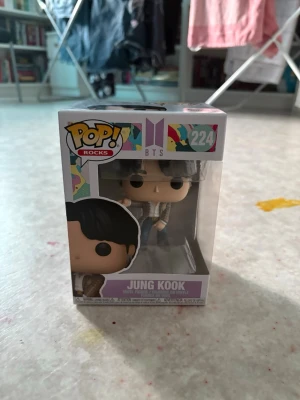  Jung Kook Funko Pop - Jung Kook från BTS Funko Pop bär en brun rutig väst med vita och beige detaljer. Västen har klassisk passform och är i ett tyg som ser ut som bomull eller polyester. Perfekt för dig som gillar coola och trendiga detaljer inspirerade av K-pop. Helt ny. Oöppnad 