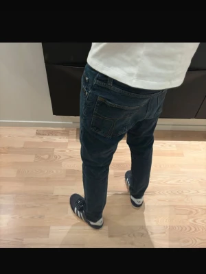 Mörkblå tiger of sweden jeans - Säljer ett par mörkblå tiger of sweden jeans med klassisk femficksdesign och slim passform. Jeansen har en enkel look utan slitningar eller mönster, perfekta till sneakers och t-shirt. Materialet är mjukt och stretchigt för extra komfort.