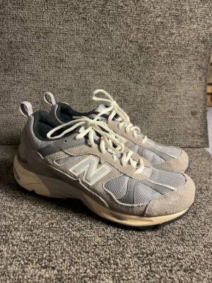 Grå New Balance 878 sneakers strl 38 - Säljer ett par grå New Balance 878 sneakers i storlek 38. Skorna har en mix av mocka och mesh, vita snören och en chunky beige sula. New balance logga på sidan och svart innersula. Perfekta för dig som gillar streetwear.