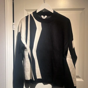 Svart och vit stickad tröja från Object - Säljer en svart och vit stickad tröja från Object med grafiskt mönster. Tröjan har lång ärm, rund halsringning och en loose passform. Perfekt för dig som gillar en unik look med coola kontraster. Superskön med 50% viskos. Rymlig i storleken.