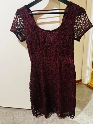 Vinröd spetsklänning från Hollister XS - Supersöt vinröd kortklänning från Hollister i storlek XS. Klänningen har ett detaljerat spetsmönster, rundad urringning och korta ärmar. Perfekt för dig som gillar romantisk stil och vill sticka ut lite extra.