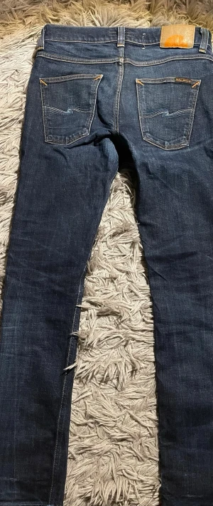 Nudie Jeans Slim 31/32 - Säljer ett par mörkblå ”Lean Dean” från Nudie Jeans i modellen slim fit. Dry denim vilket är typ som Raw denim, omsydda i benen och lagade på baksidan. Jeansen är slim i passformen.