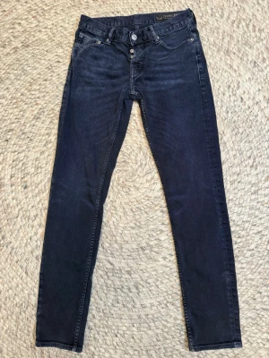 Mörkblå Care Label Bodies 214 jeans - Säljer ett par mörkblå jeans från Care Label, modell Bodies 214. De har klassisk femficksdesign, raka ben och snygga kontrastsömmar. Jeansen är tillverkade i mjukt denimtyg och har normal passform med midwaist. Perfekta till en avslappnad look.