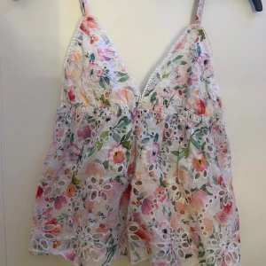 Blommig topp från Gina Tricot - Supersött blommigt linne från Gina Tricot med broderade spetsdetaljer och justerbara axelband. Passar perfekt till sommaren! 
