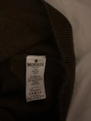 Olivgrön hoodie från Morris, M - Snygg olivgrön hoodie från Morris med huva och snörning. Tröjan är i mjuk bomull och har ribbade muddar vid ärmslut och nederkant. Klassisk passform och diskret Morris-logga på bröstet. Perfekt för en chill och stilren look.