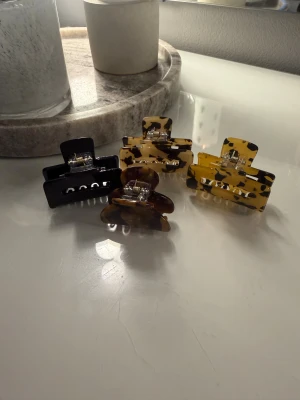 Fyra små hårklämmor  - Säljer fyra hårklämmor som inte kommer till användning. Helt nya, tre är från Kicks medan en är från Normal. Perfekta för att sätta upp halva håret med. Sitter bra i håret. Hör gärna av dig vid frågor🤎