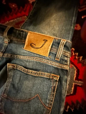 Blå jeans från Jacob Cohen - Snygga blå jeans från Jacob Cohen med klassisk femficksdesign och kontrastsömmar. Jeansen har en läderpatch med J på bakfickan och silverfärgad knapp framtill. Tillverkade i mjukt denimtyg för en bekväm passform.