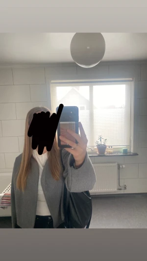 Grå kappa i ullmix - Säljer en stilren grå kappa med rak passform och öppen framsida. Jackan har långa ärmar och är tillverkad i en mjuk ullmix som passar perfekt för kyligare dagar. Enkel och clean look som funkar till det mesta.