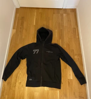 Svart Sail Racing kofta - Svart Sail Racing-hoodie med hel dragkedja. Den passar bäst till sköna personer o är perfekt för chill dagar, skolan eller när du bara vill vara bekväm alltså. Pris kan diskuteras vid snabb affär! Men chilla med att sänka priset mycket. Passar bra s, och m