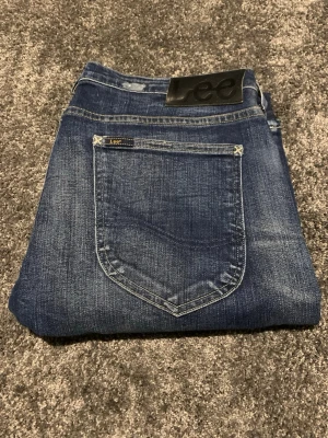 Blå skinny jeans från Lee - Snygga blå jeans från Lee med slitna detaljer och ljusa partier framtill. Klassisk femficksmodell med Lee-logga på bakfickan och svart patch i midjan. Jeansen har smal passform.
