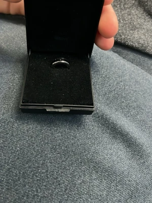 Ingen väst synlig på bilderna - Bilderna visar en ring i en Trendhim-ask, men ingen väst finns med. Kan därför inte ge någon beskrivning av väst utifrån dessa bilder.