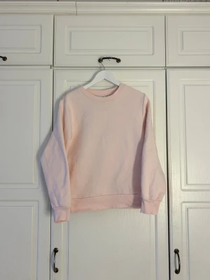 Ljusrosa sweatshirt i bomull💖 - En enkel och snygg ljusrosa sweatshirt med rund hals och ribbade muddar vid ärmslut och nederkant. Tröjan har en klassisk passform och är tillverkad i mjuk bomull, perfekt för chill dagar. Långärmad och utan tryck eller mönster.