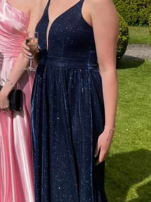 Glittrig balklänning  - En lång mörkblå, glittrande balklänning. Köpt i Polen, använd en gång av min syster på hennes bal 💃Passar en ganska lång person, kanske 1,70!