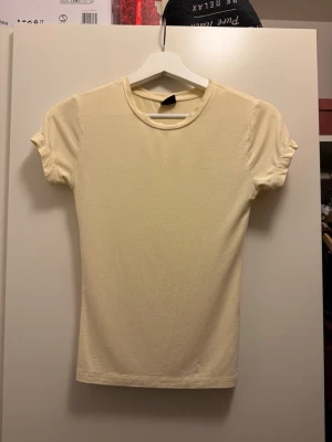Beige t-shirt från Gina Tricot XS - Säljer en enkel och stilren beige t-shirt från Gina Tricot i storlek XS. T-shirten har rund hals, korta ärmar och är gjord i mjuk bomull. Passformen är normal och tyget är slätt utan mönster eller detaljer. Perfekt för dig som gillar minimalistisk stil.