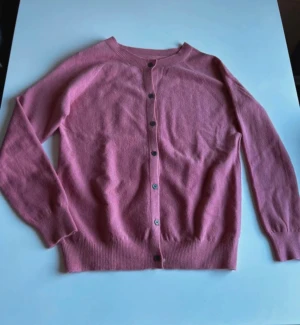 2 stycken koftor med knappar - Två stilrena koftor i beunmelerat och rosa med rund hals och knäppning framtill. Båda har långa ärmar och ribbade muddar vid ärmslut och nederkant. Perfekta att slänga på sig när det är lite kyligt ute. Mjukt material som känns skönt mot huden. Båda för 150 eller 1 för 85.