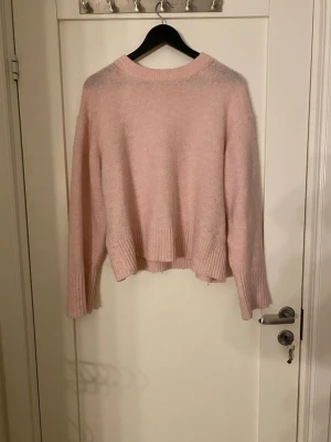 Ljusrosa stickad tröja Gina Tricot - Supermysig ljusrosa stickad tröja från Gina Tricot med ribbade muddar vid ärmslut och nederkant. Tröjan har en loose passform och är långärmad, perfekt för att hålla sig varm under kyliga dagar. Enkel och stilren design som är lätt att matcha.