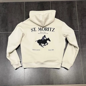 Notre Succès St.Moritz crémefärgad hoodie - Tjena säljer denna crémefärgade, oanvända hoodien från notre success med St.Moritz tryck, riktigt fet. Denna säljs inte längre i deras kollektion och är lite mer exklusiv/sällsynt. På hoodien står det M men skulle säga att den passar S också. Skriv gärna vid intresse!