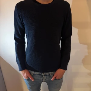 Mörkblå tröja från Bläck - Säljer en mörkblå tröja från Bläck med snyggt strukturerat tyg framtill. Tröjan har rund halsringning och långa ärmar, perfekt för lager-på-lager under kyligare dagar. Enkel och stilren design som funkar till det mesta.