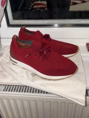 Loro Piana Flexy Walk - Snygga röda Loro Piana Flexy Walk sneakers med stickad ovandel och detaljer i skinn. Skorna har snörning, rund tå och vit platt sula. Perfekt för dig som gillar exklusiv design och vill ha något unikt på fötterna. Tillverkade i Italien.