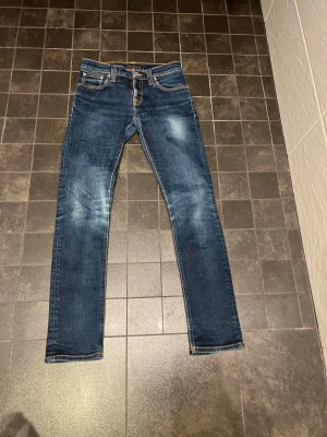 Nudie jeans - Säljer ett par blå skinny jeans från Nudie. Jeansen är i mycket bra skick utan defekter alls.  Storlek: W27 L32 som passar dig som är runt 165-175 cm lång. Bara att höra av dig om de finns några frågor. Priset är prutbart via enkel affär