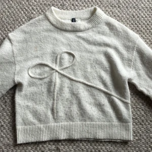 Vit stickad tröja med rosettdetalj XS - Superfin vit stickad tröja från Divided/HM i storlek XS. Tröjan har en unik rosettdetalj framtill, ribbade muddar och rund halsringning. Perfekt för dig som gillar en söt och stilren look. Pris+frakt. DMa för fler bilder vid behov. 