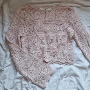 Ljusrosa stickad tröja från H&M - Supersöt ljusrosa stickad tröja från H&M med genombrutet mönster och vågig kant nertill. Tröjan har lång ärm och är perfekt för lager-på-lager. Snygg till både jeans och kjol för en chill look.