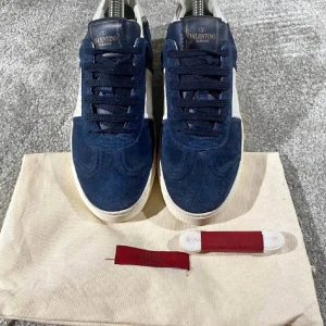 Valentino Flycrews - Snygga Valentino Flycrews sneakers i mörkblå mocka och vitt skinn. Klassisk låg modell med snörning, vita detaljer och coola nitar på hälen. Storlek 36,5 och är i nästan helt nytt skick. Säljs för 2199kr