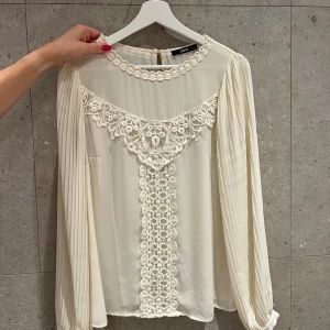 Blus med broder i mitten - Cremefärgad blus i storlek S med broderi i mitten. På den första bilden ser man blusens broderi under ex en kavaj 🌟🌟🌟