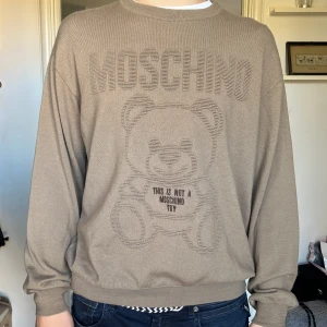 Beige Moschino stickad tröja i ull - Säljer en beige stickad tröja från Moschino med ikonisk björn och texten 'This is not a Moschino toy' framtill. Tröjan har relaxed fit. 