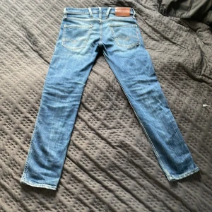 Replay Anbass jeans blå, stl 28 - Säljer ett par blå Replay Anbass jeans i storlek 28. Klassisk femficksmodell med snygga slitningar och raka ben. Jeansen har normal passform och är tillverkade i mjukt denimtyg som sitter skönt hela dagen.